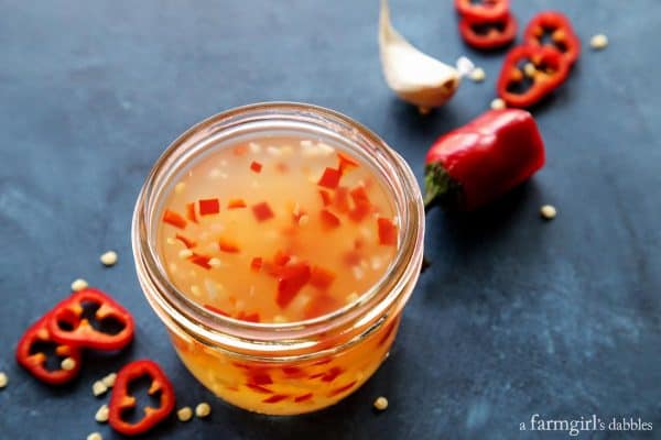 a jar of sweet chili sauce, plus red chili peppers and garlic