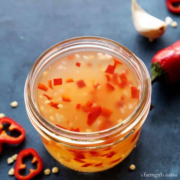 a jar of sweet chili sauce, plus red chili peppers and garlic
