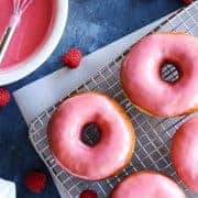 Homemade Yeast Donuts on a wire rack surrounded by fresh raspberries