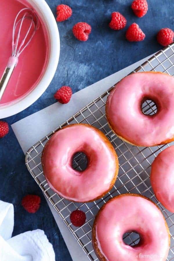 Homemade Yeast Donuts on a wire rack surrounded by fresh raspberries