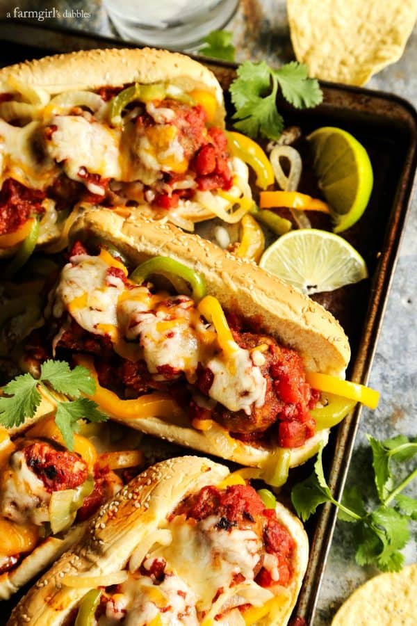 Meatball subs with peppers and melted cheese on a baking sheet