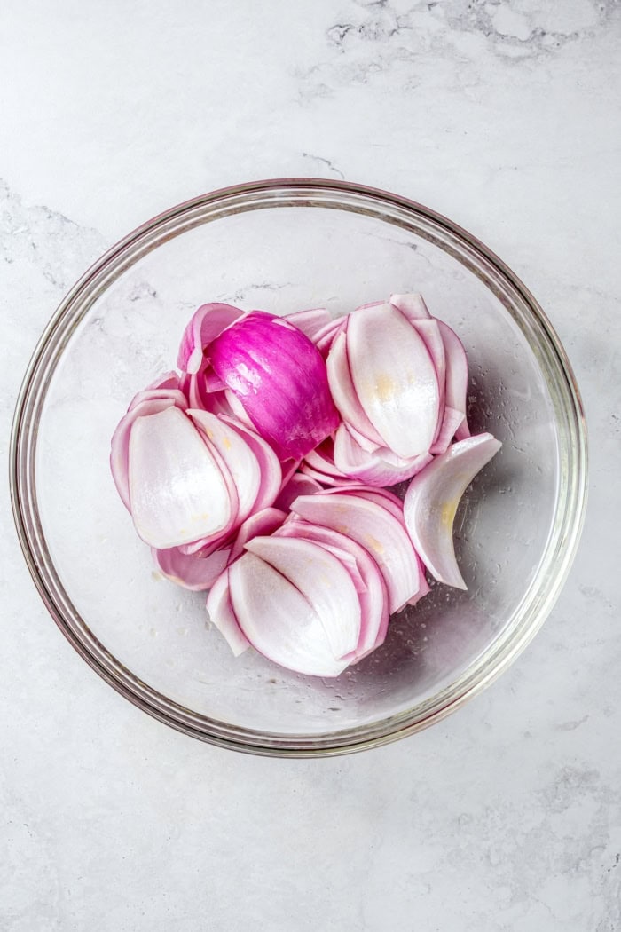 Overhead view of red onions in bowl with oil