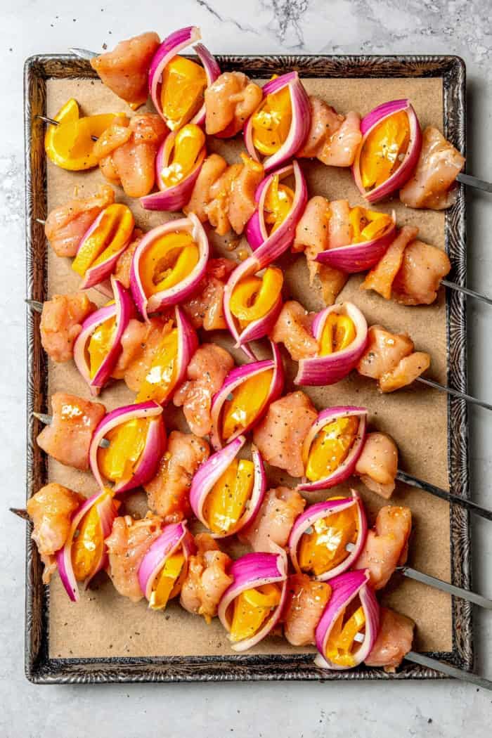 Overhead view of uncooked turkey kabobs on sheet pan