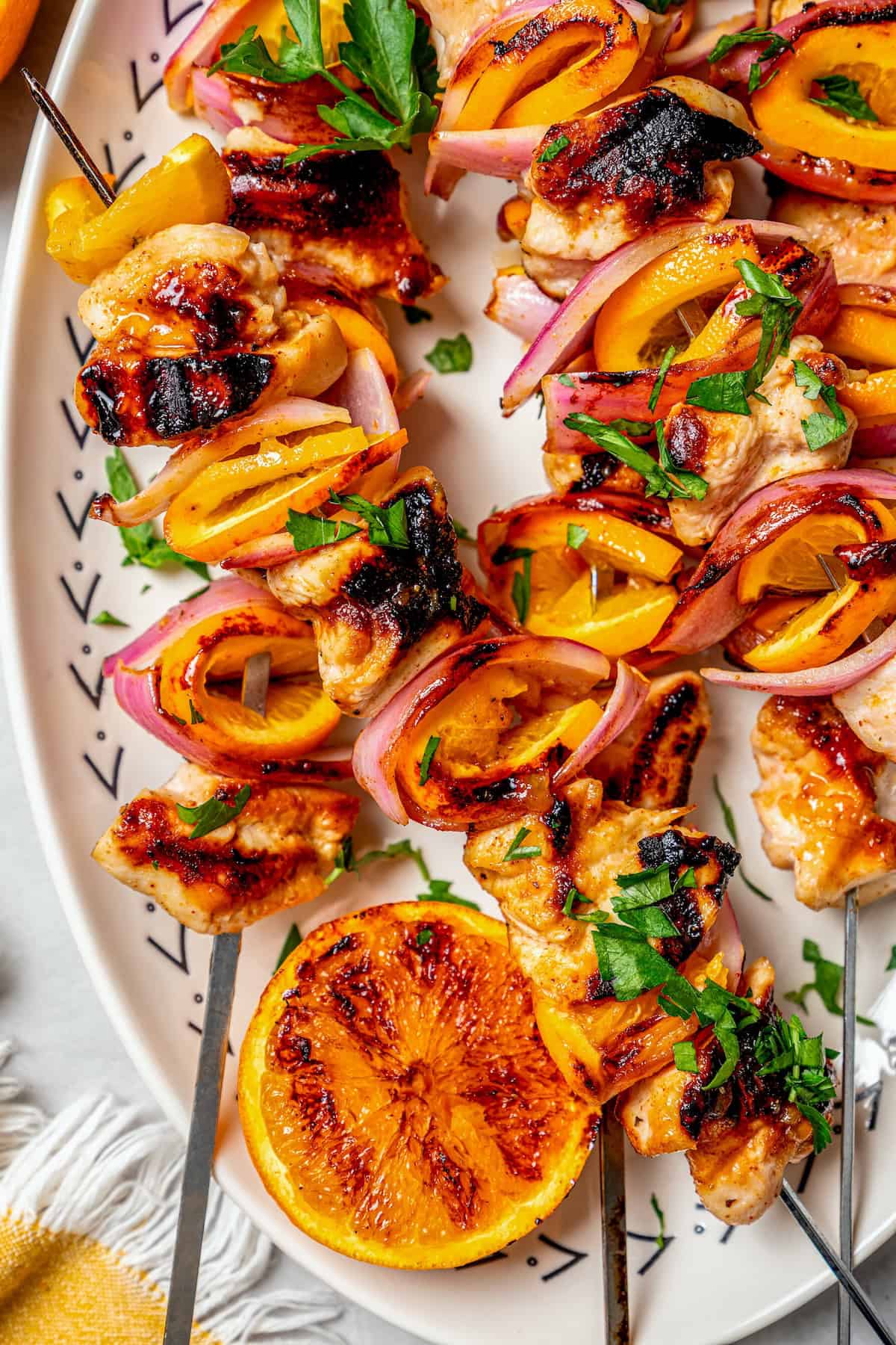 Overhead view of grilled chipotle orange turkey kabobs on platter with grilled orange half