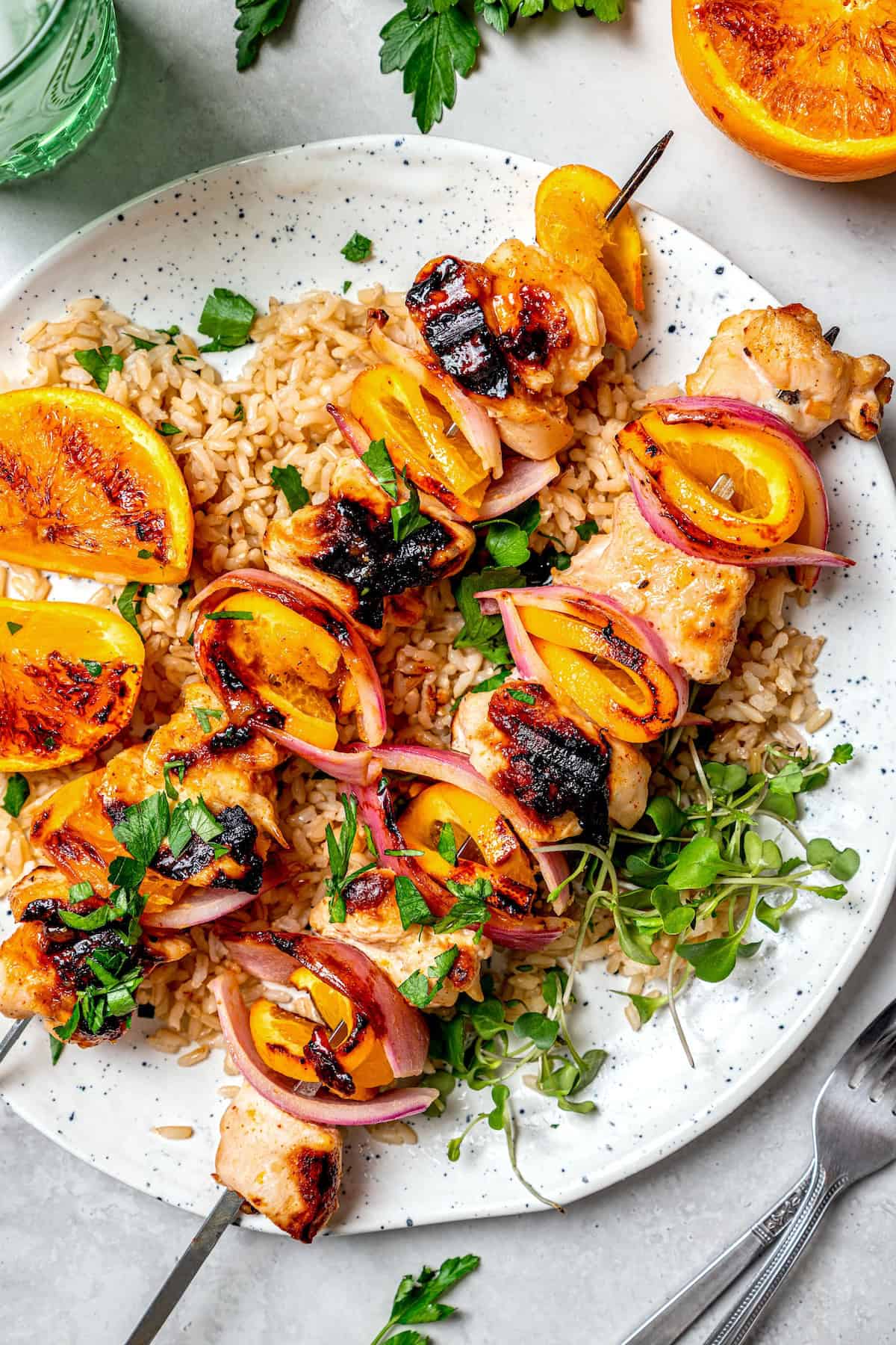 Overhead view of grilled chipotle orange turkey kabobs on plate with rice and microgreens