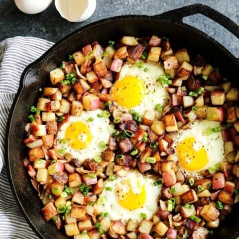 skillet of fried potatoes hash with eggs and bacon