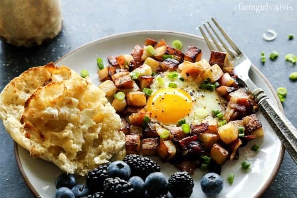 English muffins and Fried Potatoes with Bacon and Eggs on a plate with fresh berries