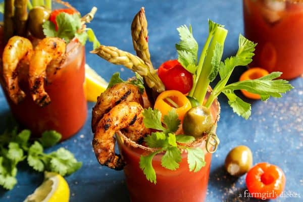 A glass of Bloody Mary with Grilled Jalapeno Shrimp, Celery, and Olives