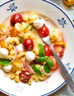 Caprese pasta salad in bowl with fork.