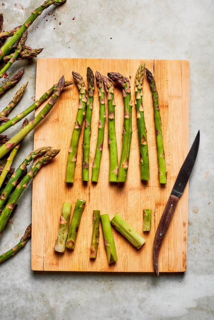 Trimmed asparagus on cutting board with knife.