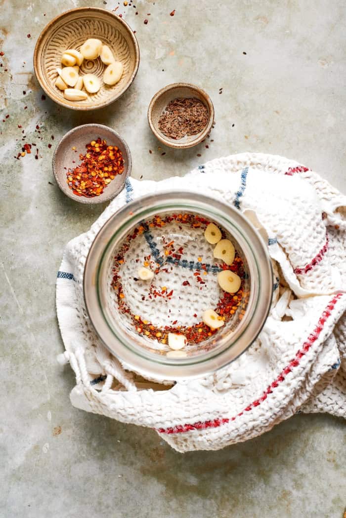 Garlic, red pepper flakes, and dill seeds in jar.