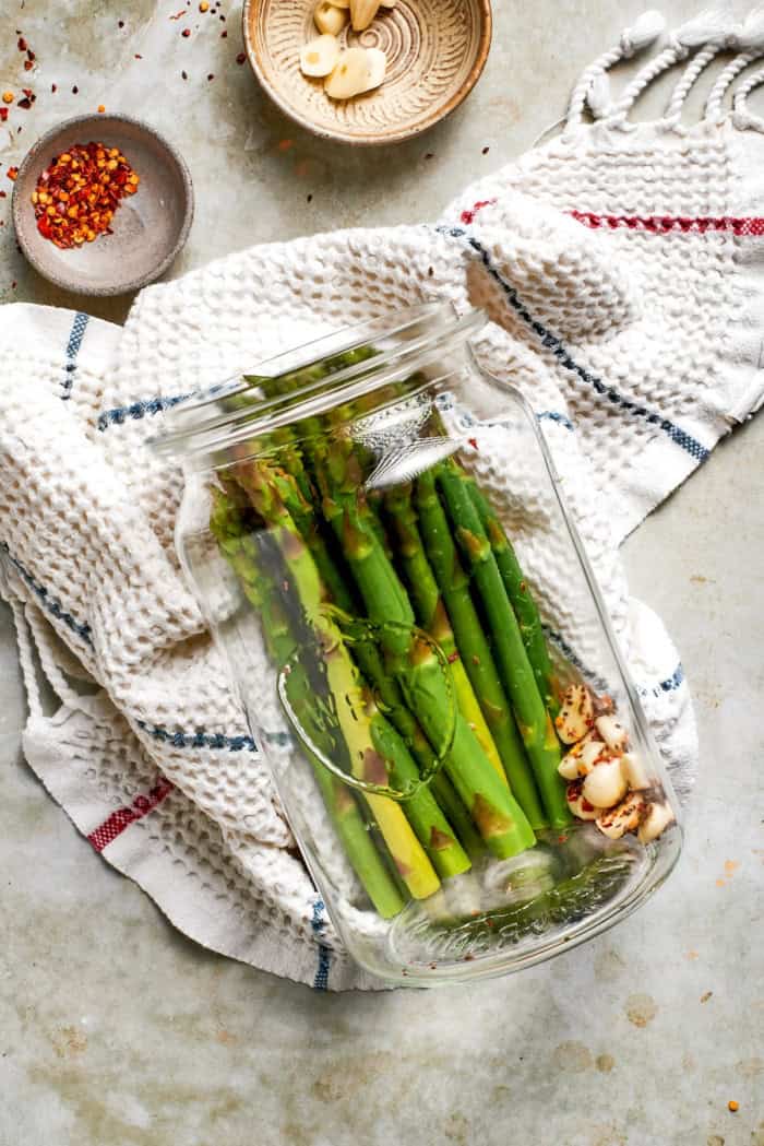 Asparagus, red pepper flakes, and garlic in jar.