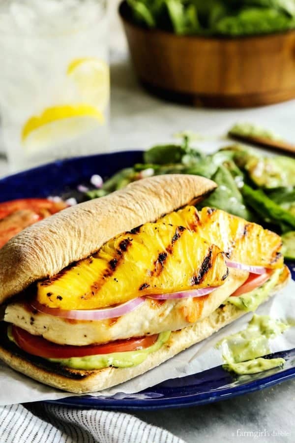Grilled Chicken and Pineapple Sandwich with Creamy Basil Sauce on a blue plate with a salad