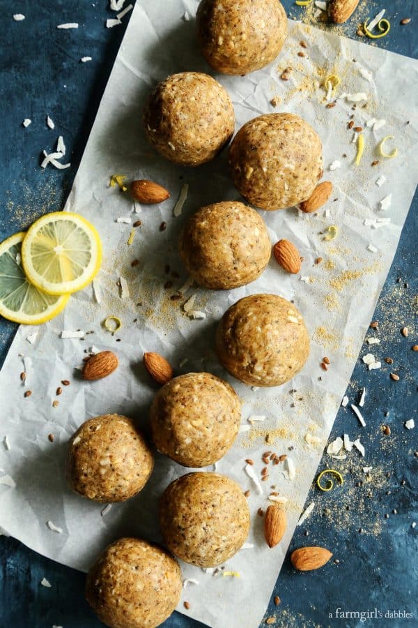 Aloha Protein Balls on parchment paper with almonds, lemon slices and coconut