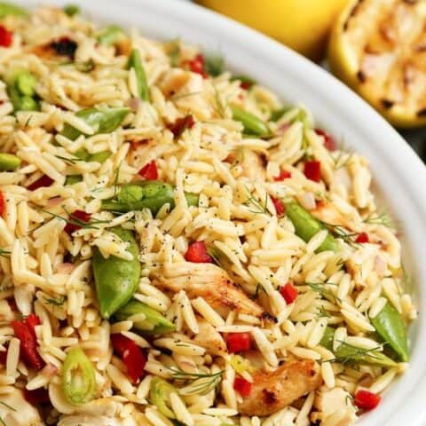 A close-up of a bowl of grilled chicken and lemon orzo salad