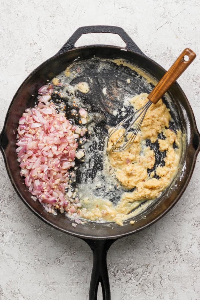 Whisking roux in skillet with red onions.