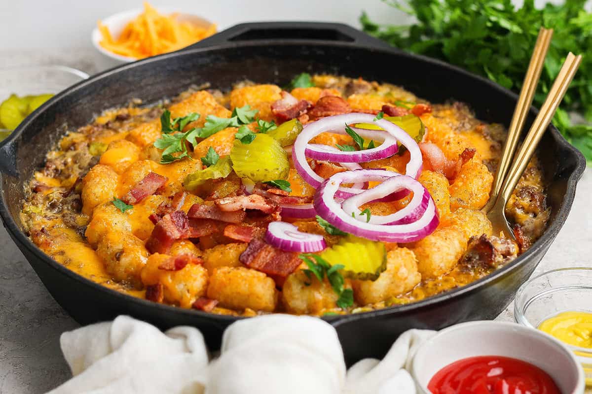 Skillet of bacon cheeseburger casserole with two spoons.