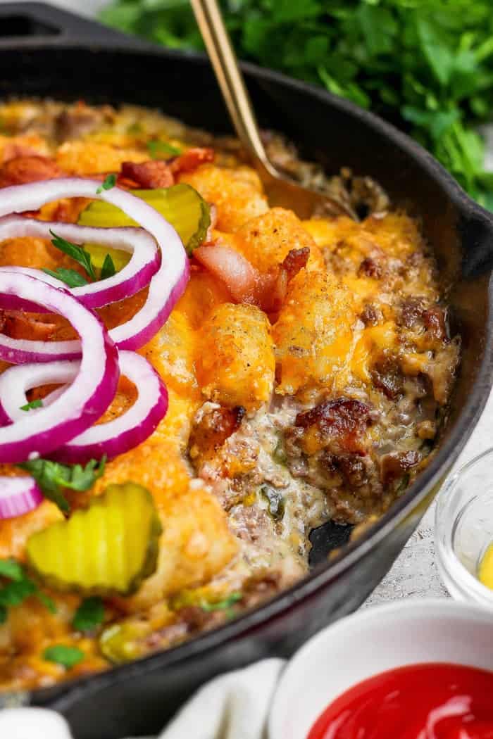 Spoon in skillet of bacon cheeseburger casserole.
