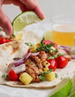 Squeezing lime juice onto grilled pork and pineapple taco