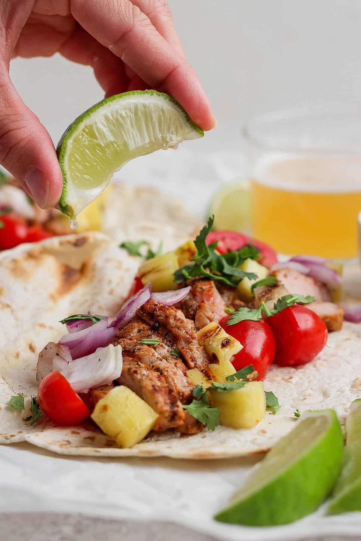 Squeezing lime juice onto grilled pork and pineapple taco
