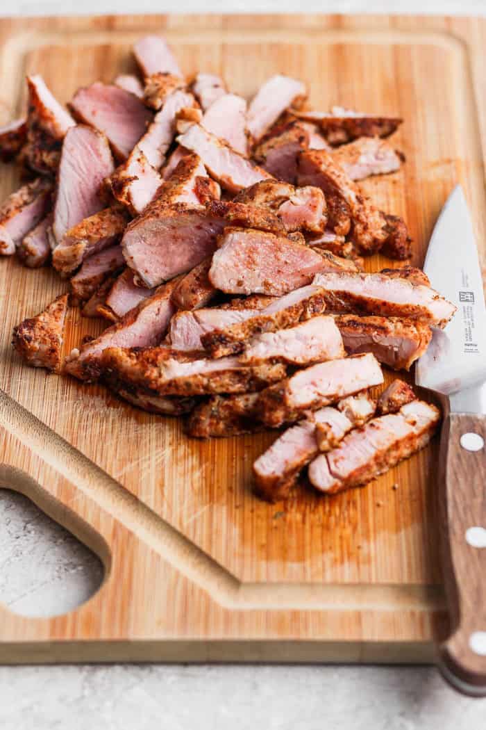 Sliced pork on cutting board with knife