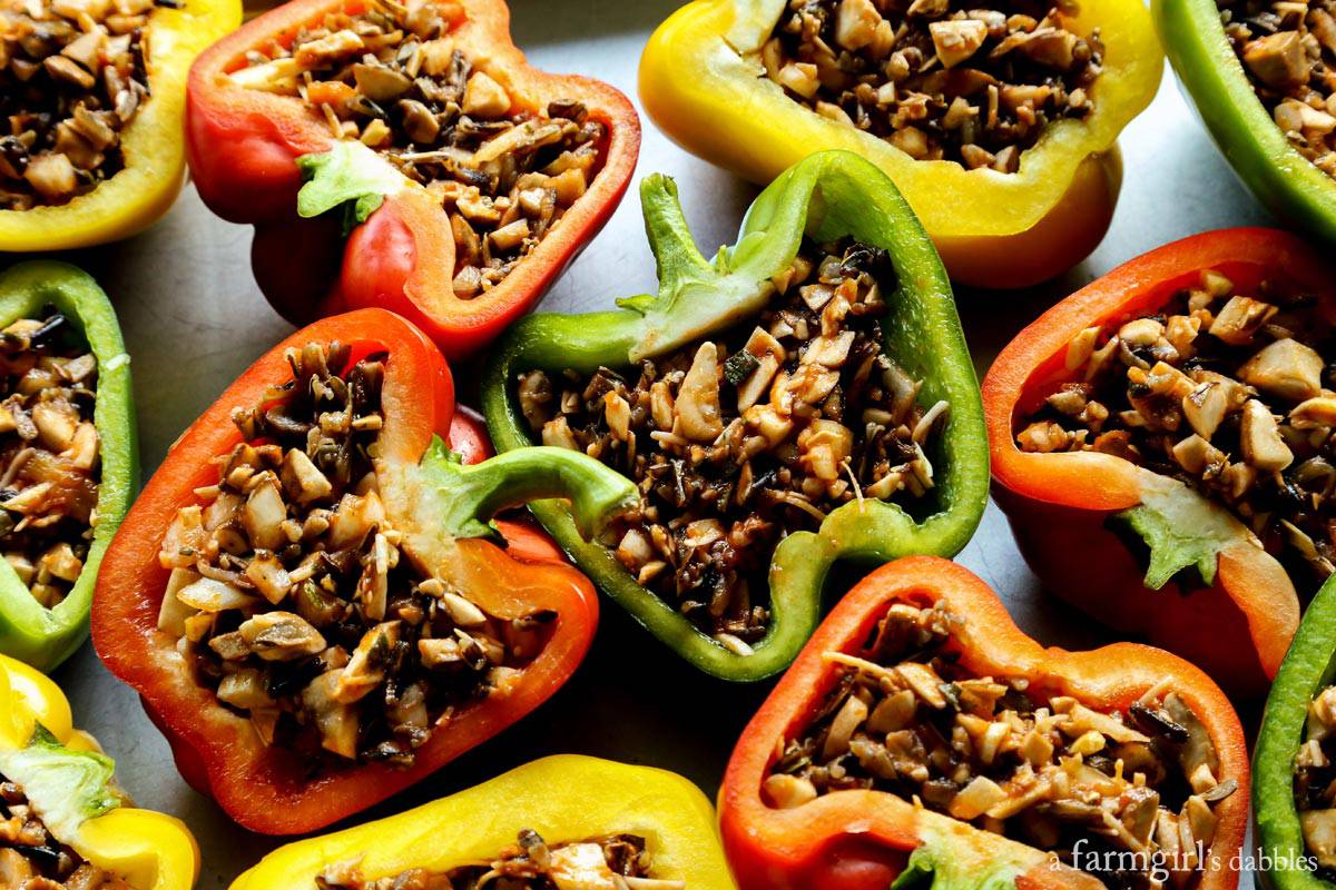 Stuffed peppers with rice are shown on a rimmed pan before being cooked.