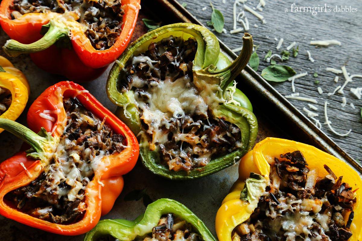 Stuffed peppers with rice and cheese and herbs on a baking pan.