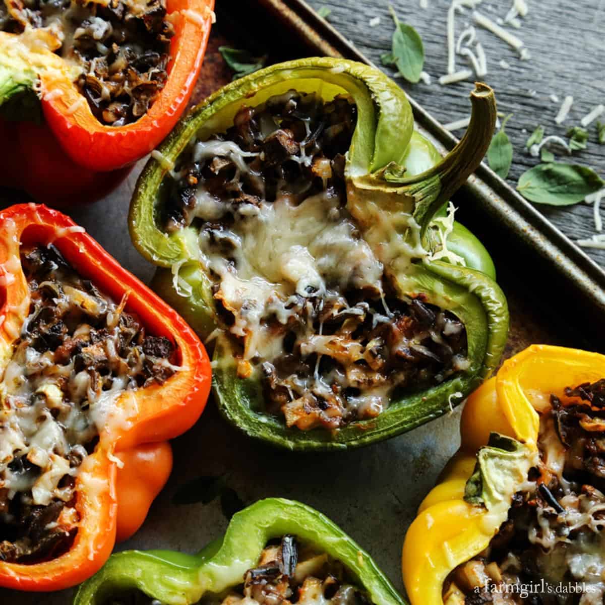 Stuffed peppers with rice are shown on a rimmed pan.