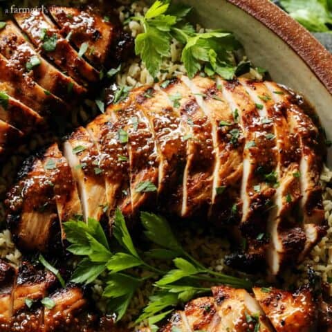 turkey tenderloin, grilled and then sliced - with brown sugar and whole grain mustard sauce, served over brown rice, on a tan pottery platter