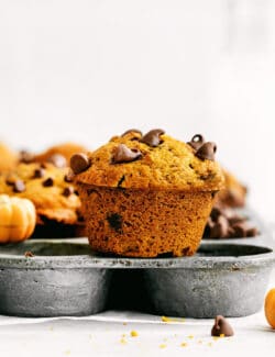 A pumpkin muffin on top of a muffin pan