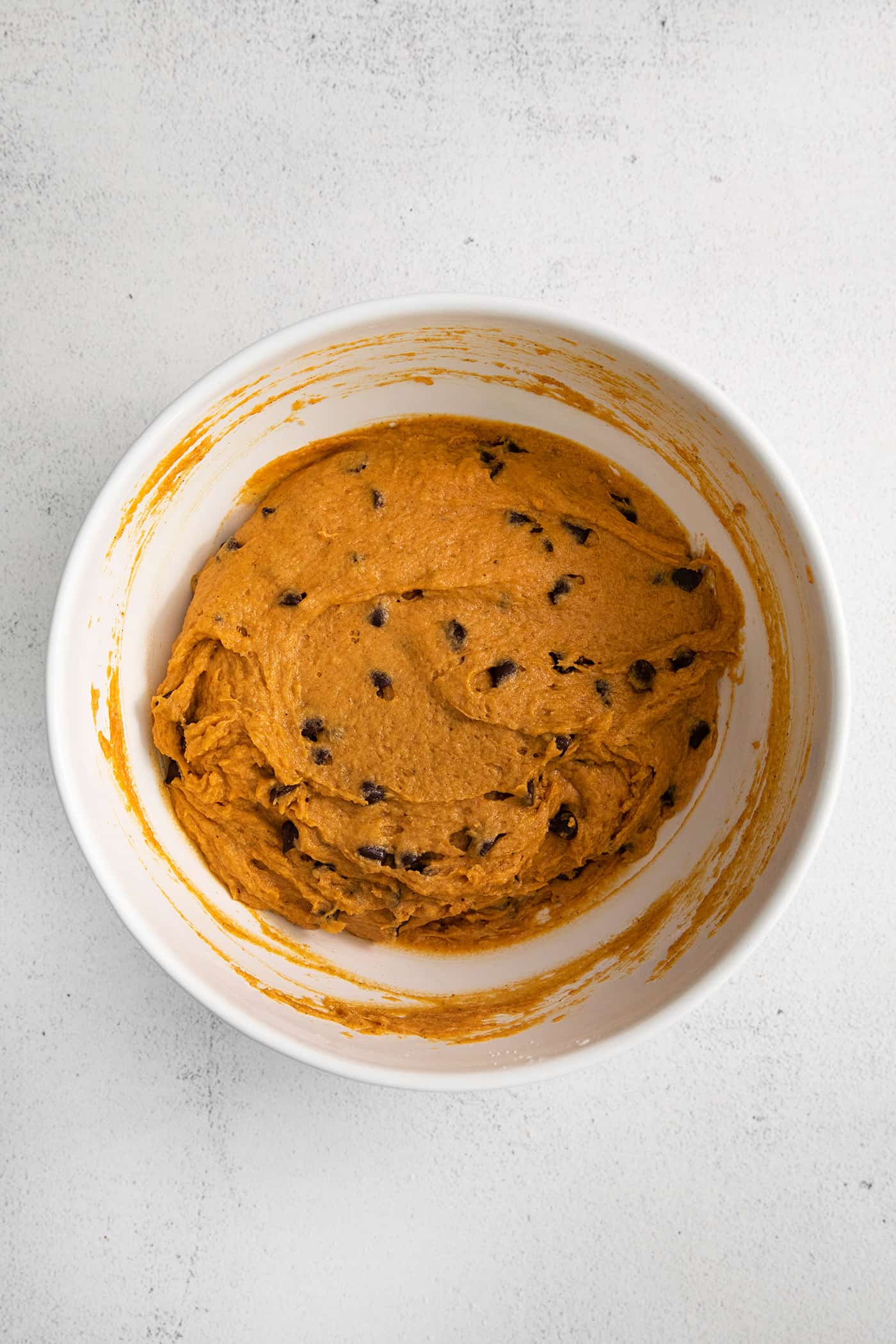 Chocolate chip pumpkin muffin batter in a white bowl