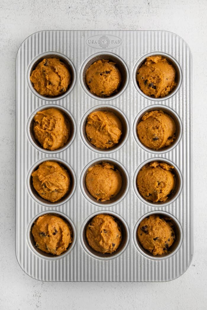Batter in the muffin tray cavities, ready to be baked.