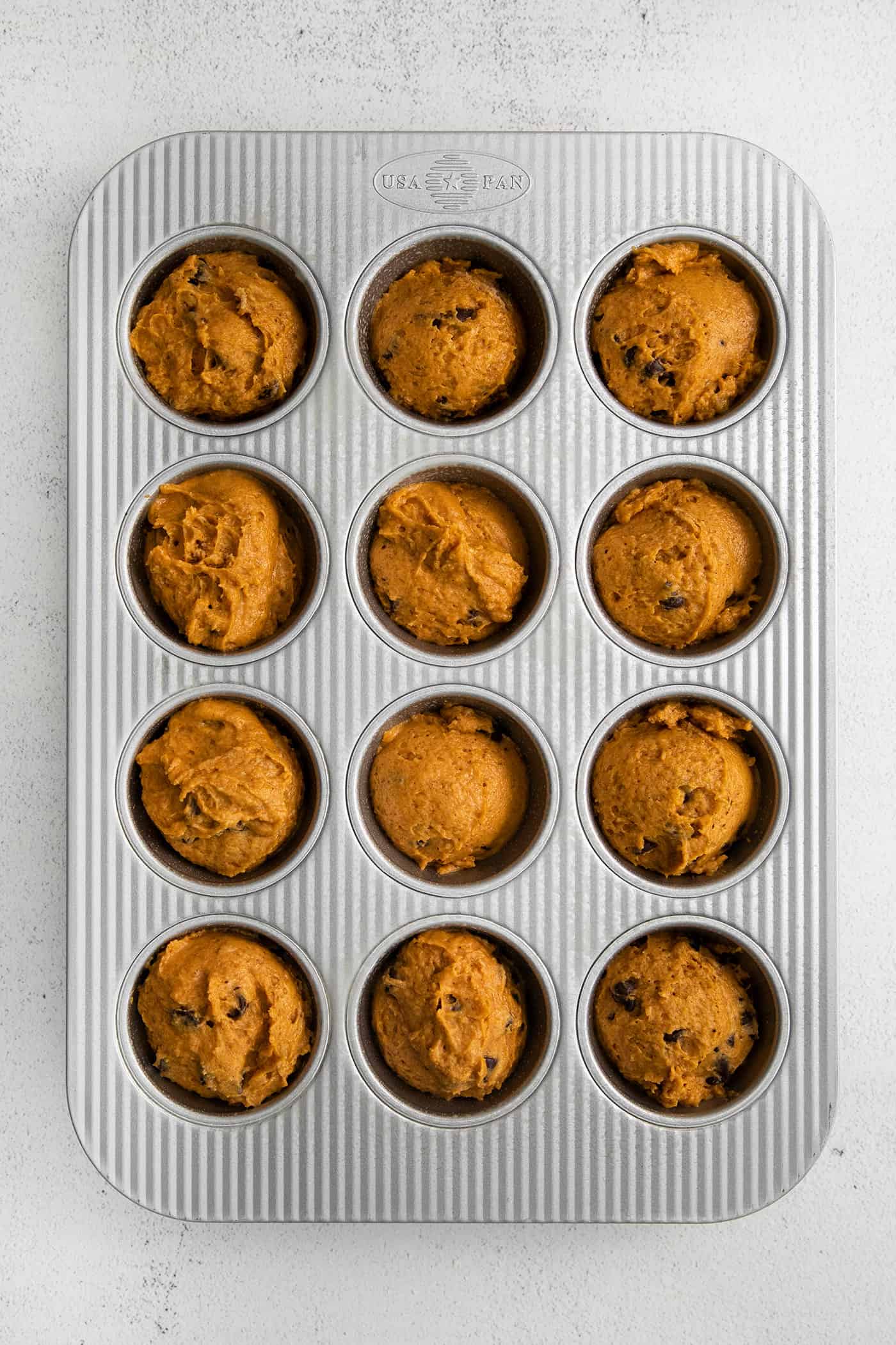 Pumpkin muffin batter in a muffin pan