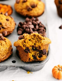 A muffin half out of a muffin pan with a bite missing