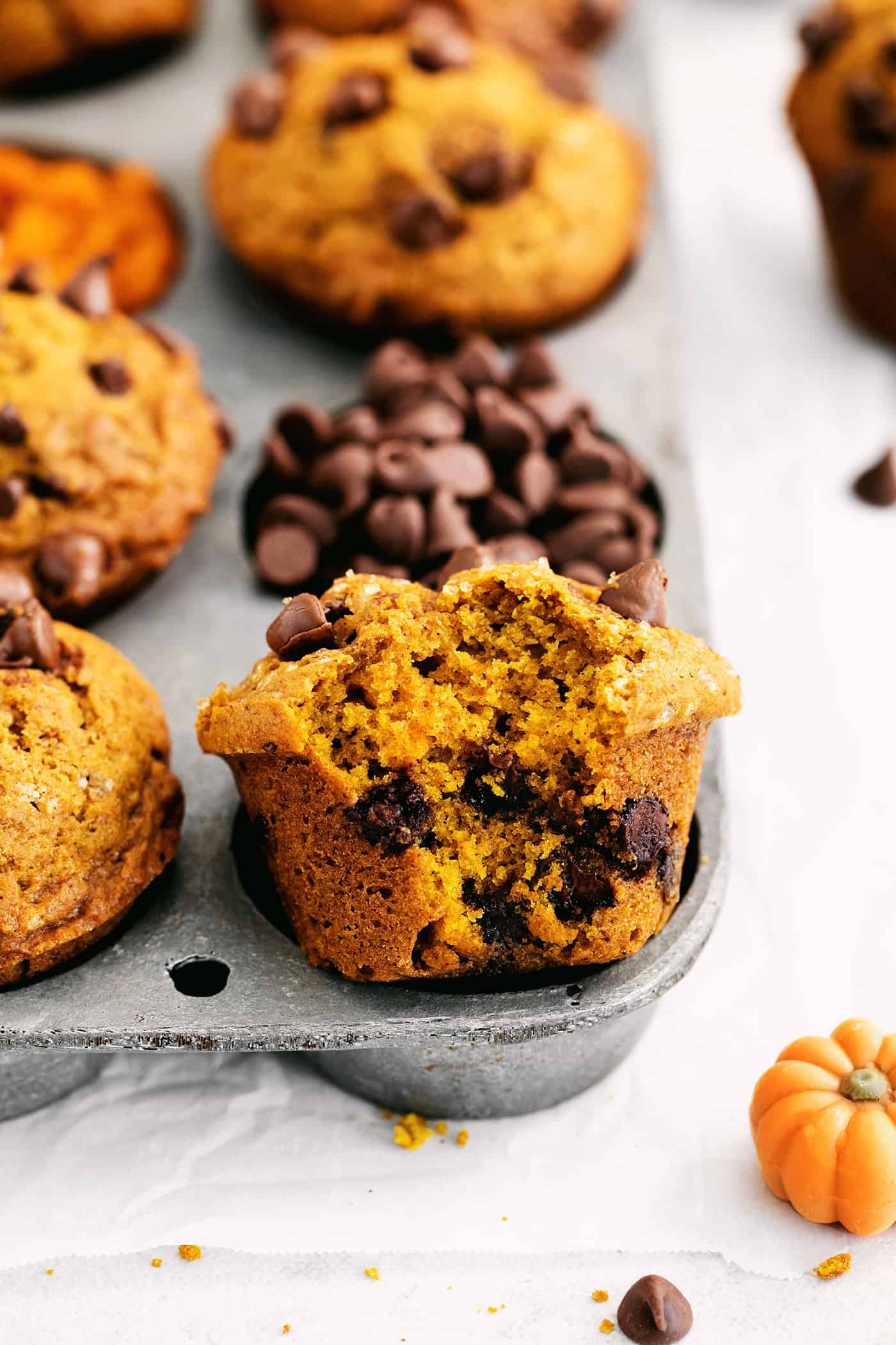 A muffin half out of a muffin pan with a bite missing