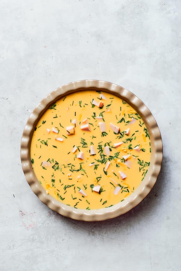 Pouring the egg mixture over the cheese and ham layers.
