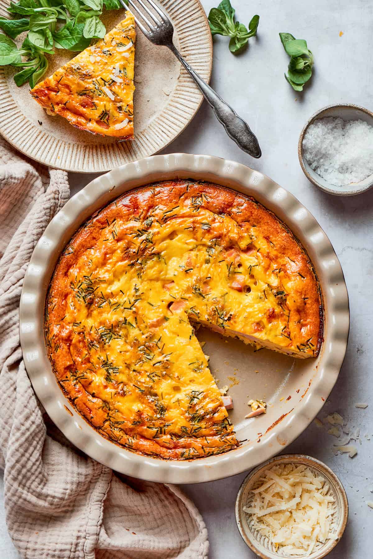 This cheesy crustless quiche recipe with ham, tangy Dijon, and chives is an easy baked dish for the holidays. Crustless quiche fresh out of the oven in the pie plate.