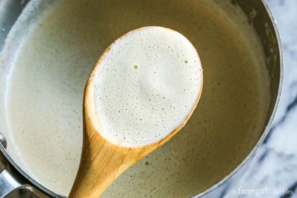 a saucepan of homemade eggnog with a wooden spoon