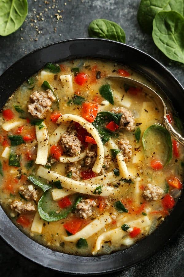 Sausage and Red Pepper Soup with Egg Noodles in a black bowl