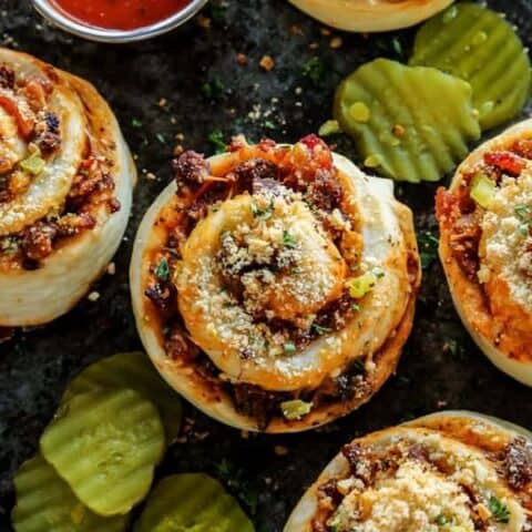 Top view of bacon cheeseburger pizza rolls topped with grated cheese and herbs