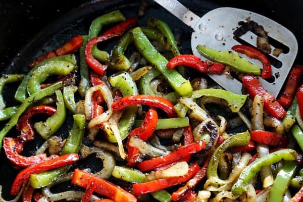 sliced sweet peppers and onions in cast iron skillet