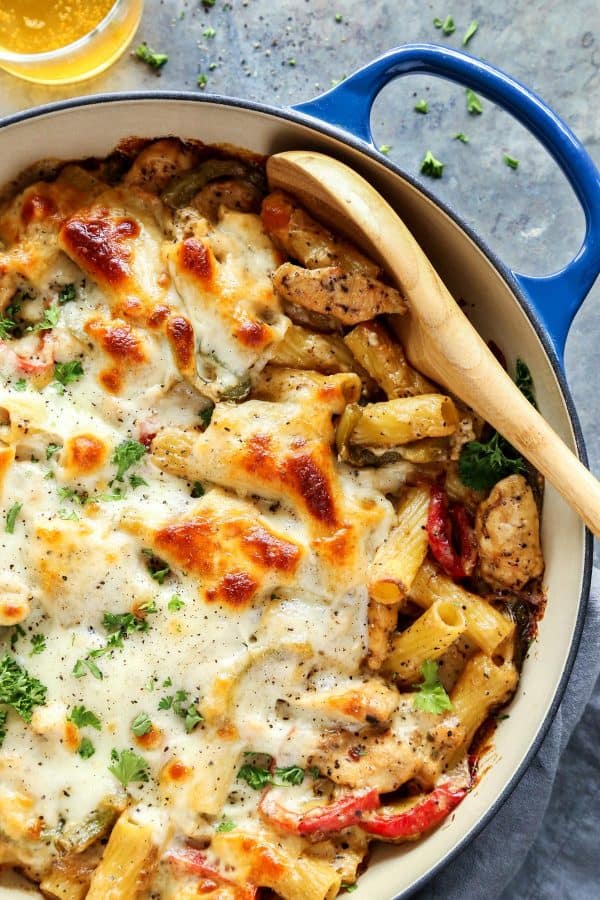 Chicken Cheesesteak Baked Ziti in blue dish, with wooden spoon