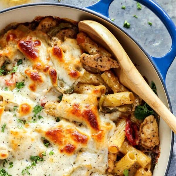 Chicken Cheesesteak Baked Ziti in blue dish, with wooden spoon