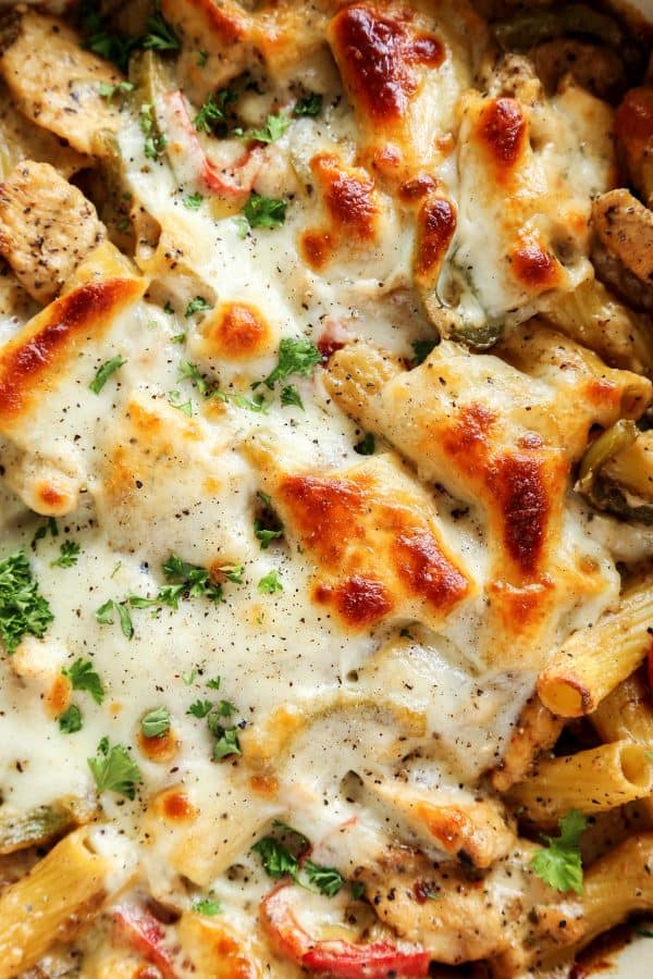 Chicken Cheesesteak Baked Ziti in blue dish, with wooden spoon