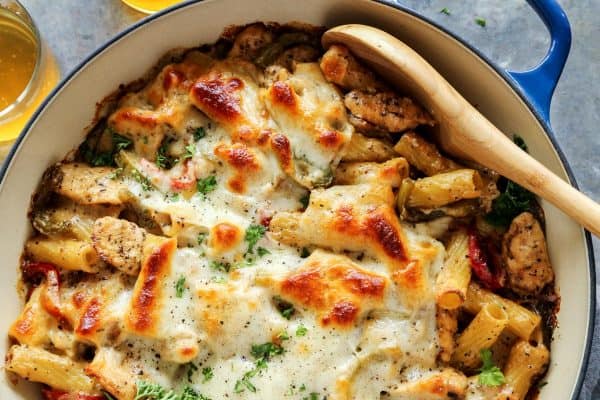 Chicken Cheesesteak Baked Ziti in blue dish, with wooden spoon