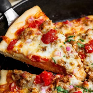 Lifting slice of skillet pizza from pan.