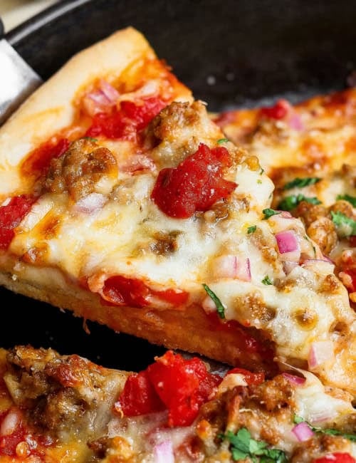 Lifting slice of skillet pizza from pan.