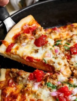 Lifting slice of skillet pizza from pan.