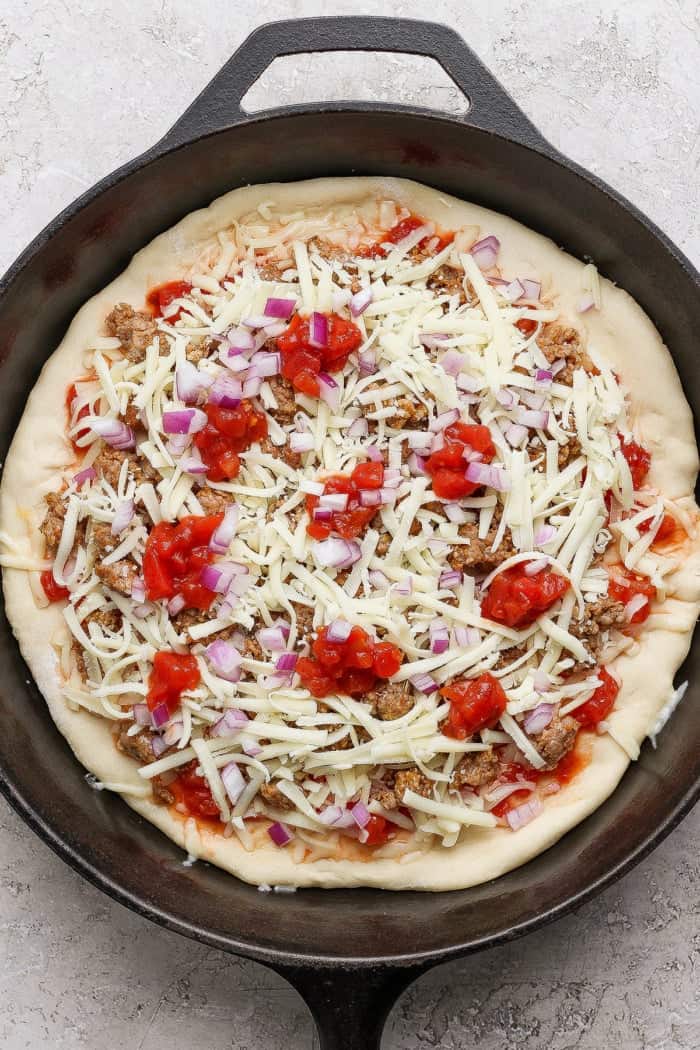 Assembled pizza in cast iron skillet before baking.
