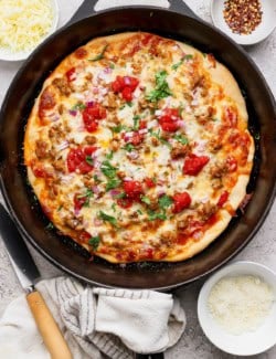 Cast iron skillet with sausage pizza.